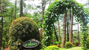 Indicador de Jardins Le Monet envoltat de vegetació exuberant i un camí de pedra.