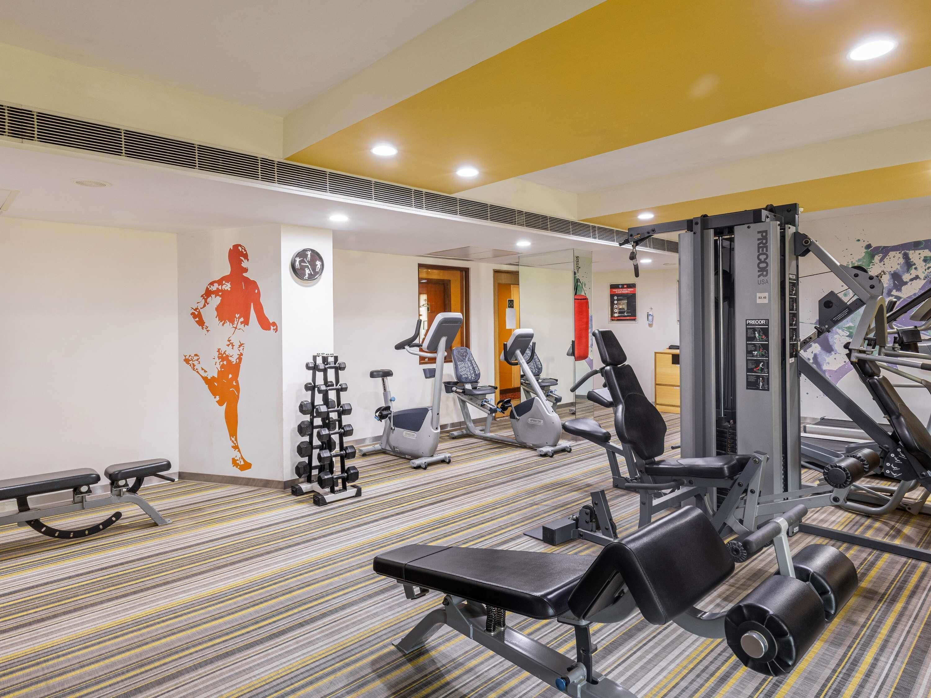 Un gimnasio con diverso equipamiento de ejercicio, que incluye mancuernas, cintas de correr y máquinas de pesas.