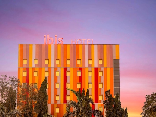 Un edificio de hotel con fachada a rayas y el nombre 'ibis Hotel' en la parte superior.