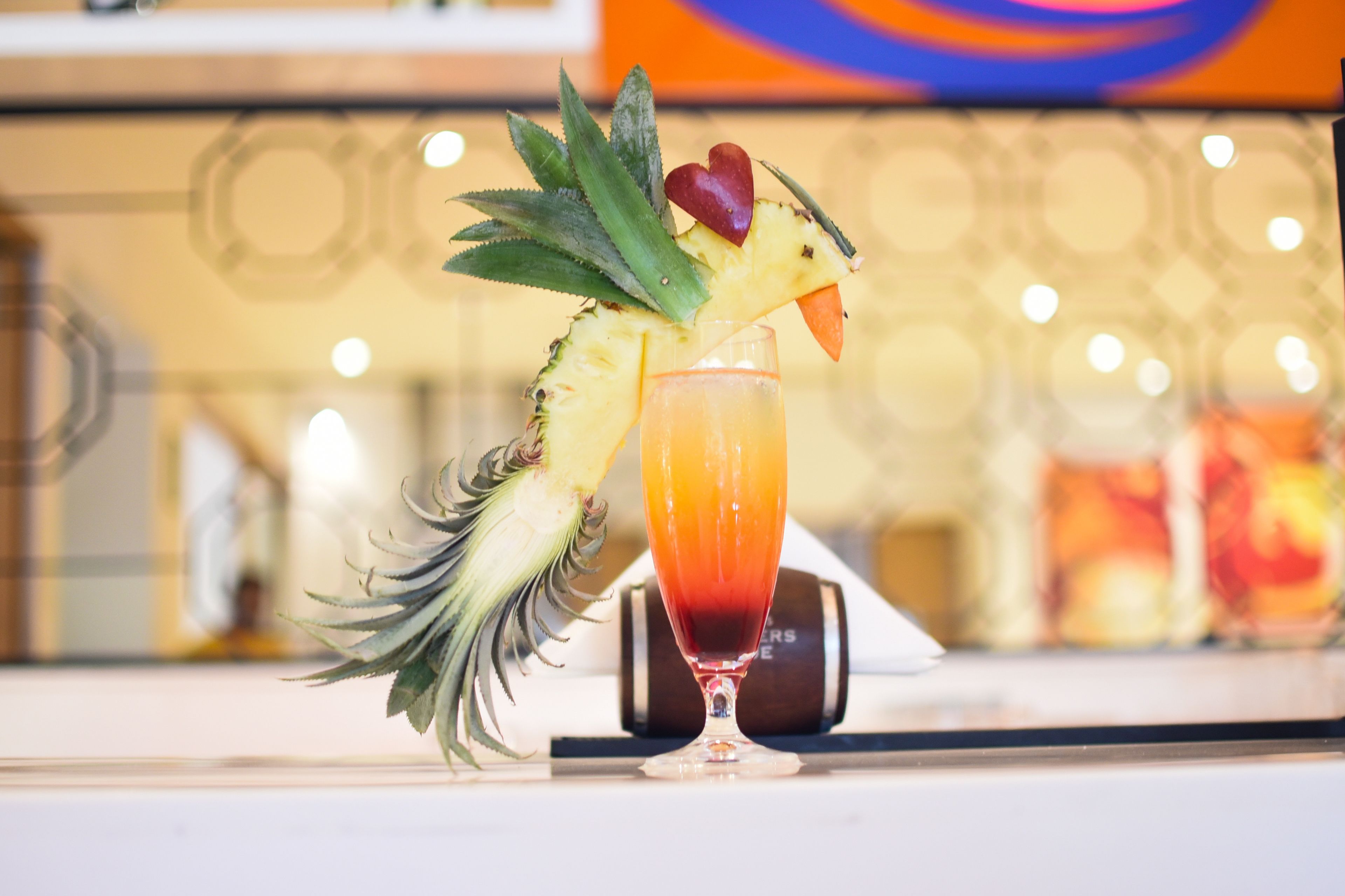 A cocktail with a pineapple garnish on a bar counter.