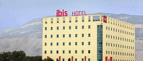 Un edificio de hotel con fachada plana, múltiples ventanas y un llamativo letrero 'ibis HOTEL' en la parte superior.