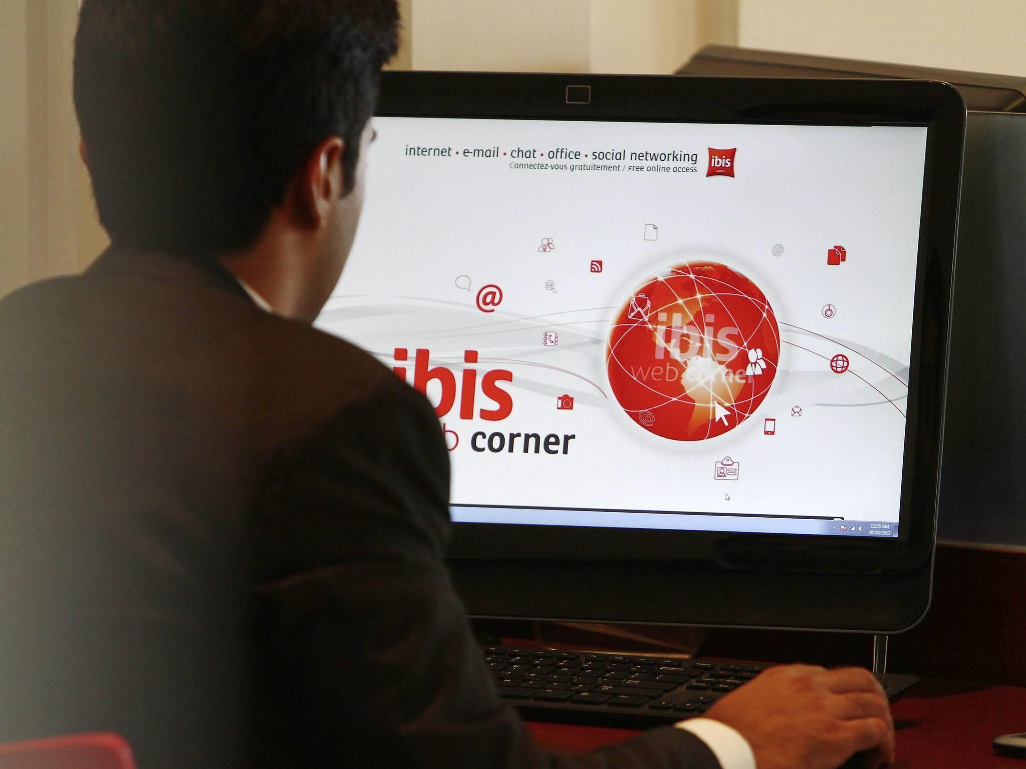 Eine Person benutzt einen Laptop, dessen Bildschirm das Wort 'ibis' und verschiedene Symbole zeigt.