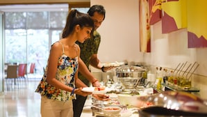A buffet setup with various food items and utensils. - ibis Navi Mumbai Hotel (Navi Mumbai)
