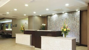 A reception area with two reception desks, a patterned wall, and a seating area in the background.