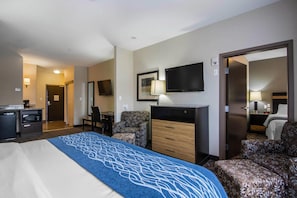 Una habitación de hotel con cama, escritorio, silla, televisor y armario.