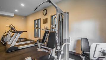 Un gimnasio con cintas de correr, máquinas de pesas y un reloj de pared.