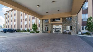 A hotel entrance with a covered walkway, stone pillars, and a parking lot. - Comfort Inn & Suites (Fort Saskatchewan)