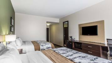 Ein Hotelzimmer mit zwei Betten, einem Fernseher, einem Schreibtisch mit Kaffeemaschine und einer Mikrowelle.