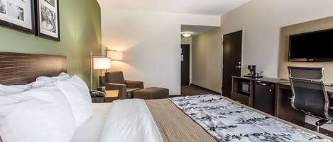 Una habitación de hotel con cama, escritorio, silla, televisor y lámpara.