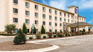 A multi-story hotel with a beige facade, a covered entrance, and a parking lot with marked spaces. - Sleep Inn & Suites Mount Olive North (Mount Olive)