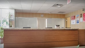 A reception area with a wooden counter, a whiteboard, and an exit sign. - New Lodge (Winnipeg)