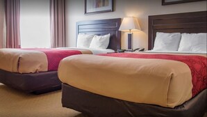 A hotel room with two beds, each with a headboard, a bedside table with a lamp, and a view of the city through the window. - New Lodge (Winnipeg)
