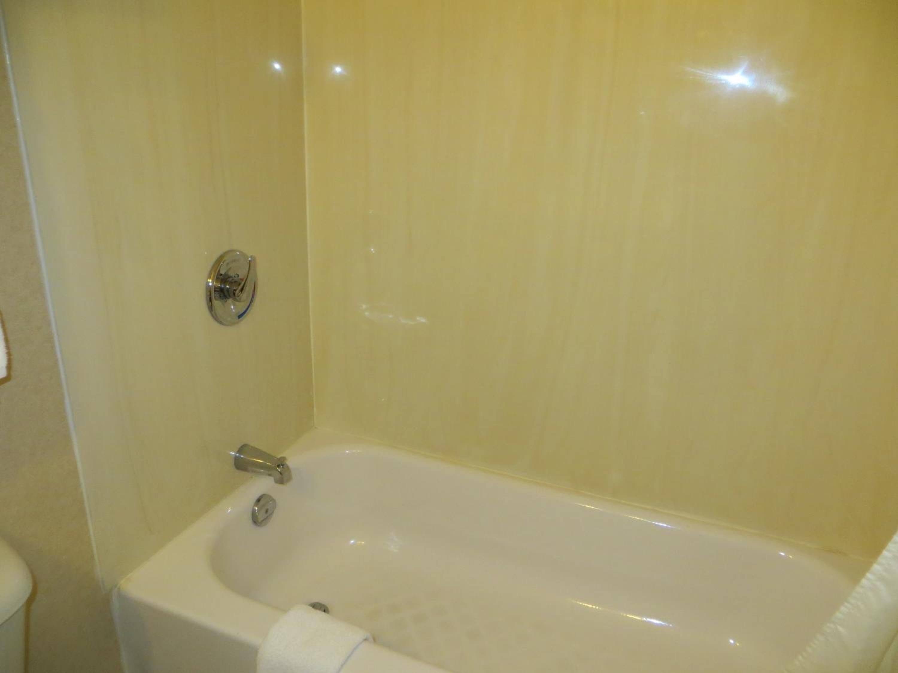 A bathroom with a bathtub, a toilet, and a shower area.