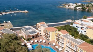 A coastal hotel with a swimming pool, sun loungers, and a view of the sea. - Porto Kalamaki Hotel (Chania)