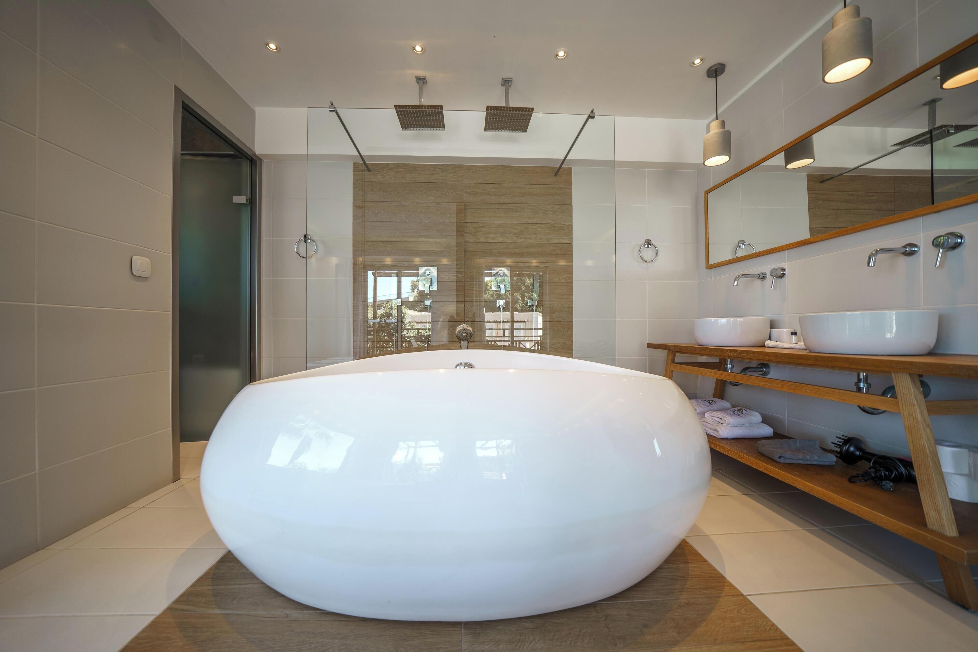 Ein modernes Badezimmer mit einer großen, ovalen Badewanne, einem Holzanbauwaschbecken mit Spiegel und einer Glasdusche.