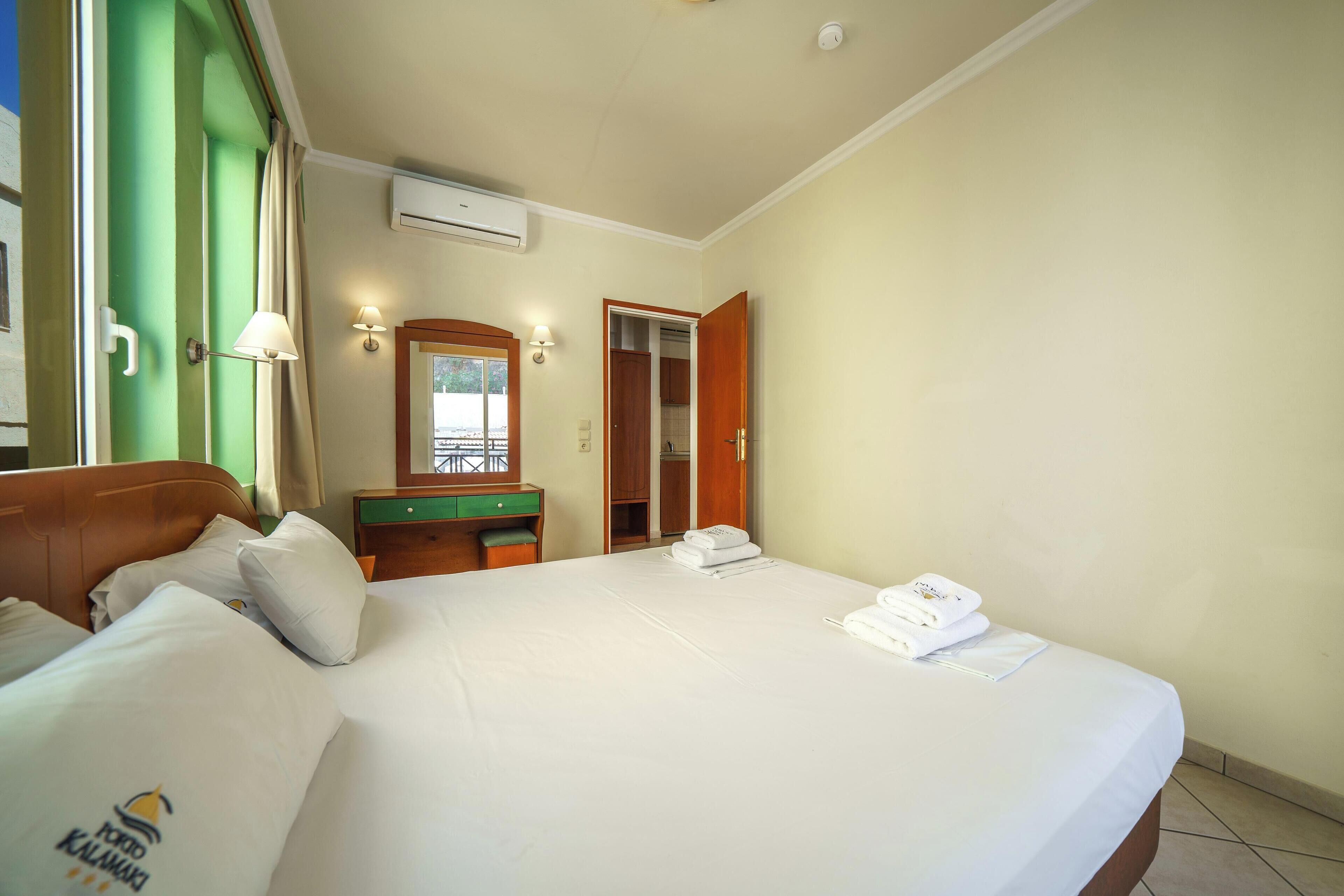 A hotel room with a bed, a desk, a mirror, and a wardrobe.