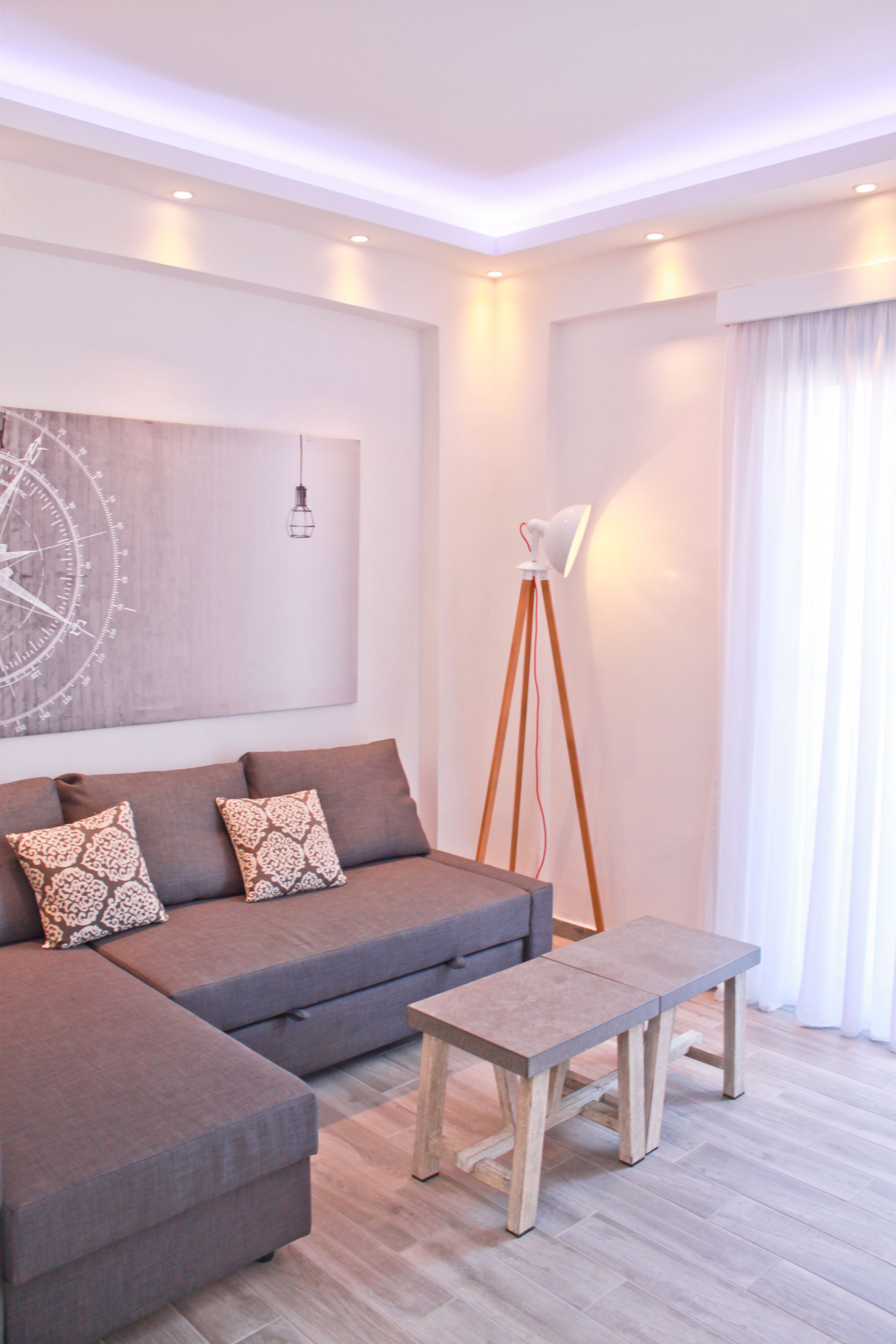 A modern living room with a sectional sofa, a wooden coffee table, a floor lamp, and a large abstract painting on the wall.