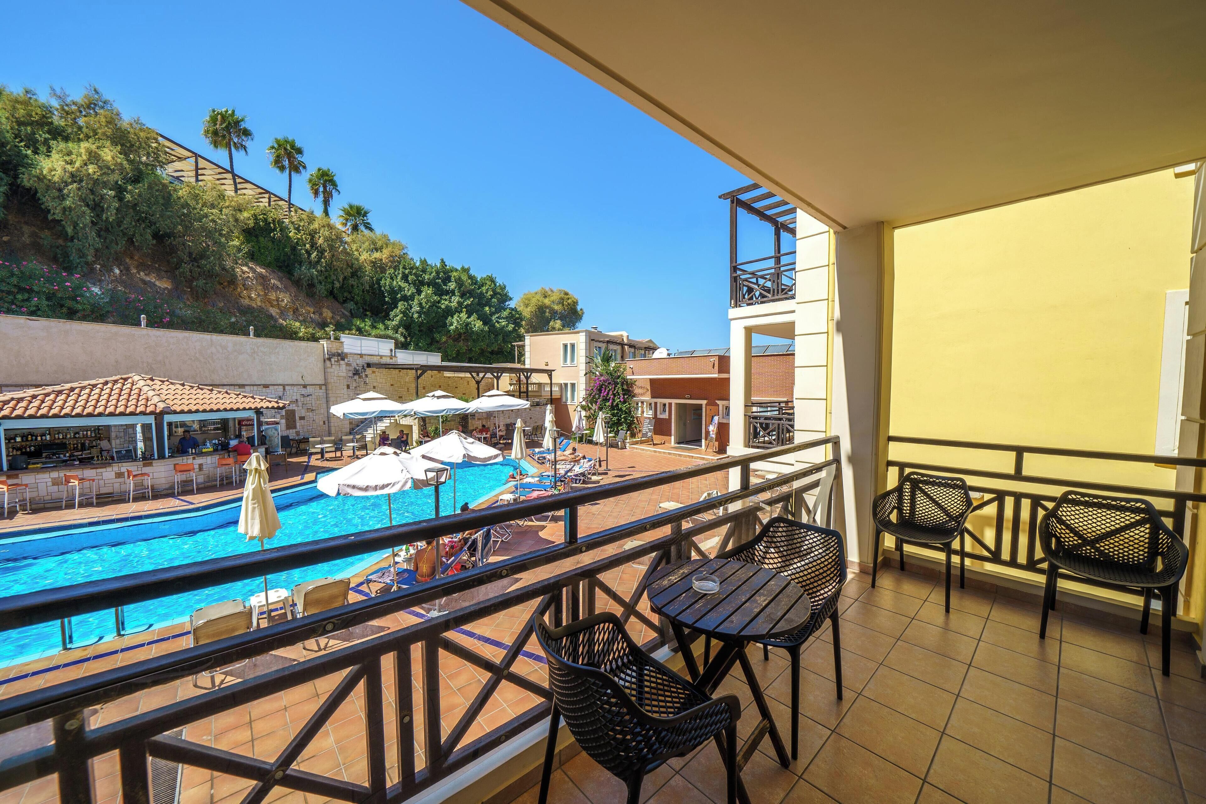 A balcony with a pool, outdoor seating, and a view of the surrounding area.