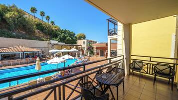 A balcony with a pool, outdoor seating, and a view of the surrounding area.