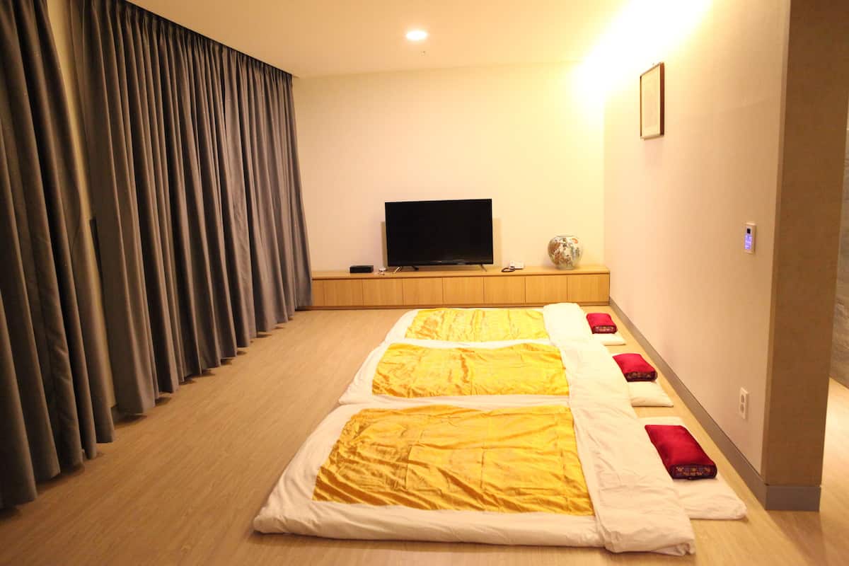 A hotel room with a large bed, a flat-screen TV, and a curtain-covered window.
