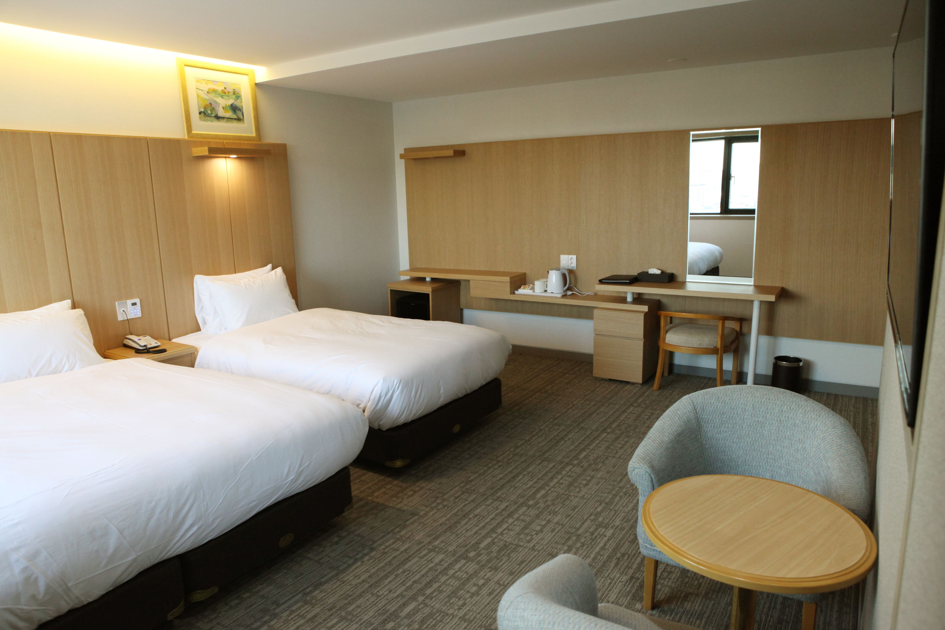 Ett hotellrum med två sängar, ett skrivbord, en stol och ett litet bord.