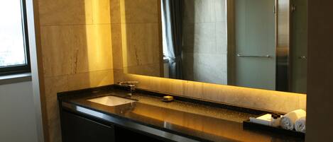 A modern bathroom with a large mirror, a sink, and a shower.
