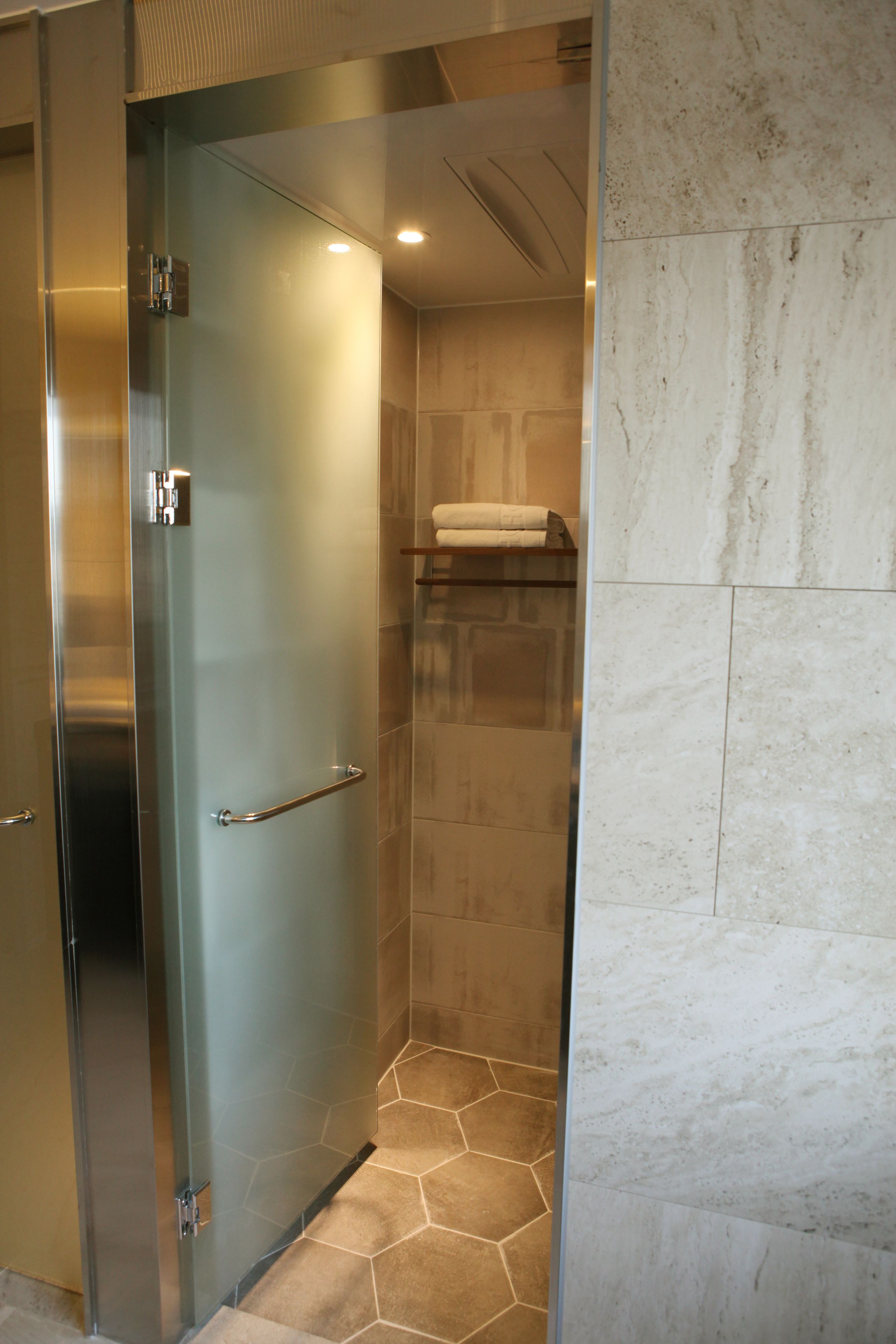 Un baño moderno con cabina de ducha de vidrio, un perchero y una pared de mármol.