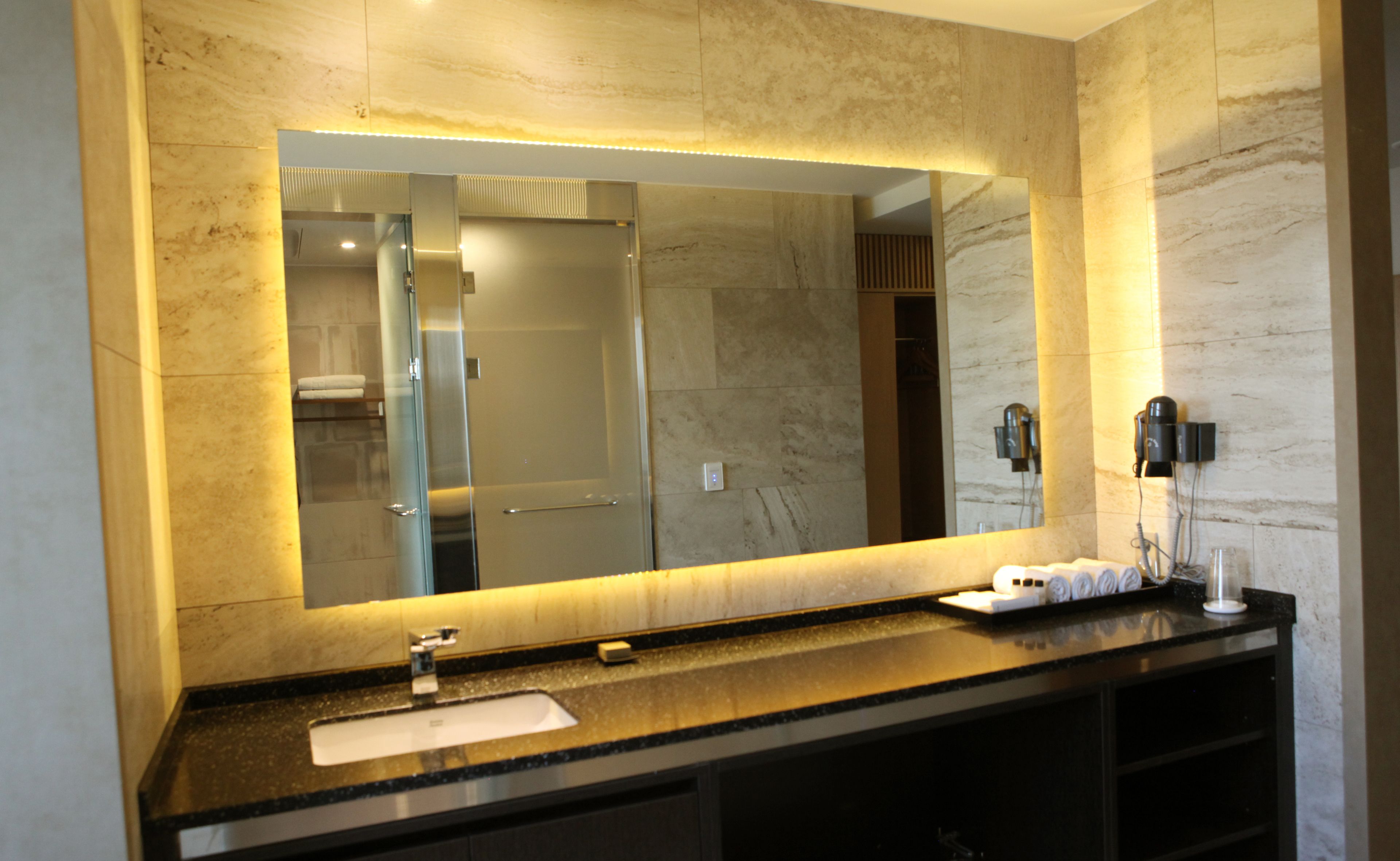 Un baño moderno con un espejo grande, un lavabo y un perchero para toallas.
