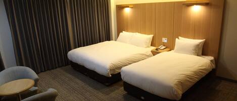 Une chambre d’hôtel avec deux lits, une petite table et une chaise.