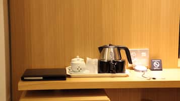 A wooden desk with a laptop, a white teapot, a black coffee maker, and a "No Smoking" sign.
