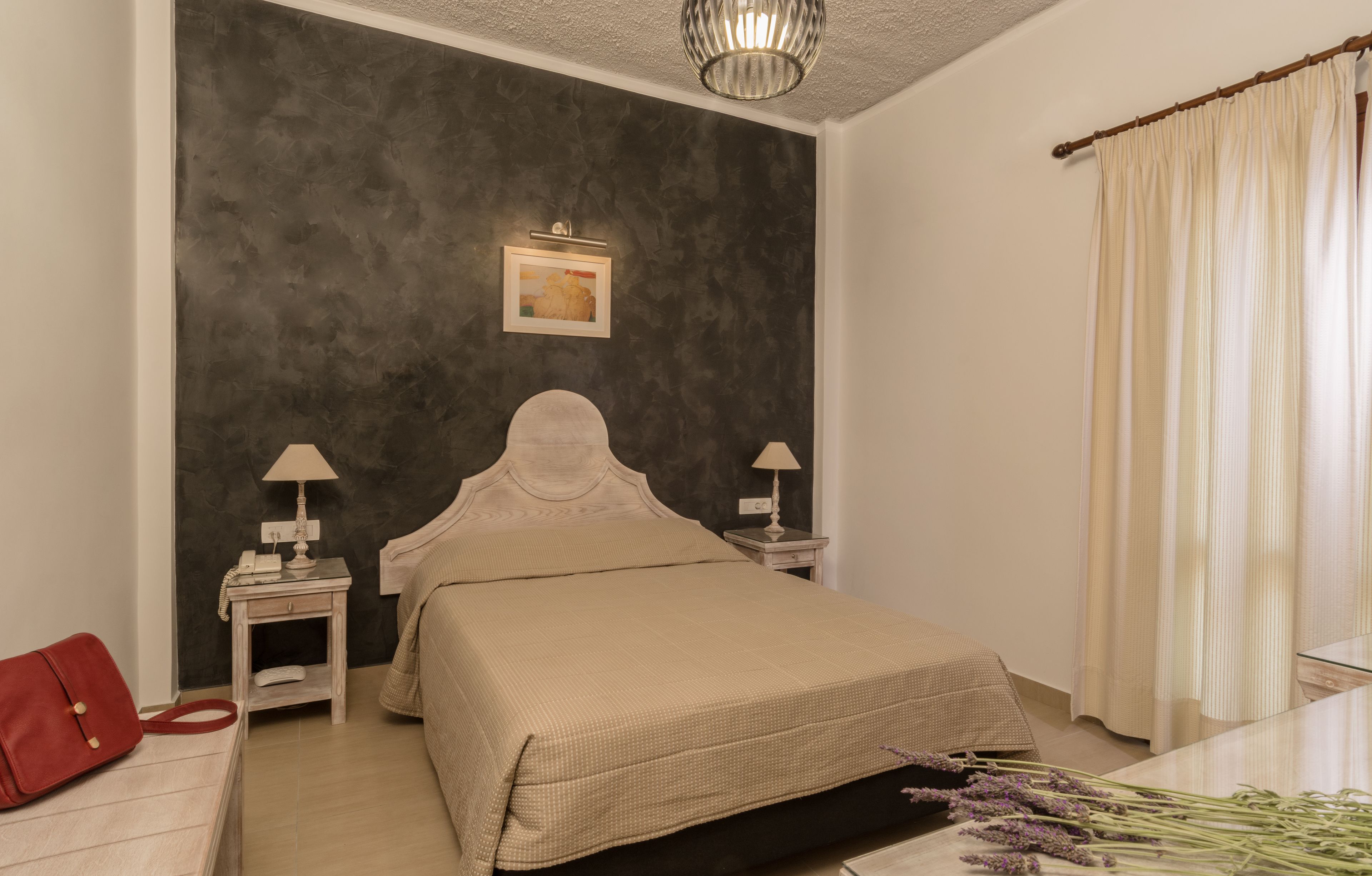 Ein Schlafzimmer mit einem Bett, Nachttischen, einer Lampe, einer roten Tasche und einem Blumenstrauß.