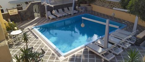 Una piscina al aire libre, sillones reclinables de piscina