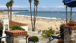 Vista de una playa con palmeras, una silla y una barandilla.