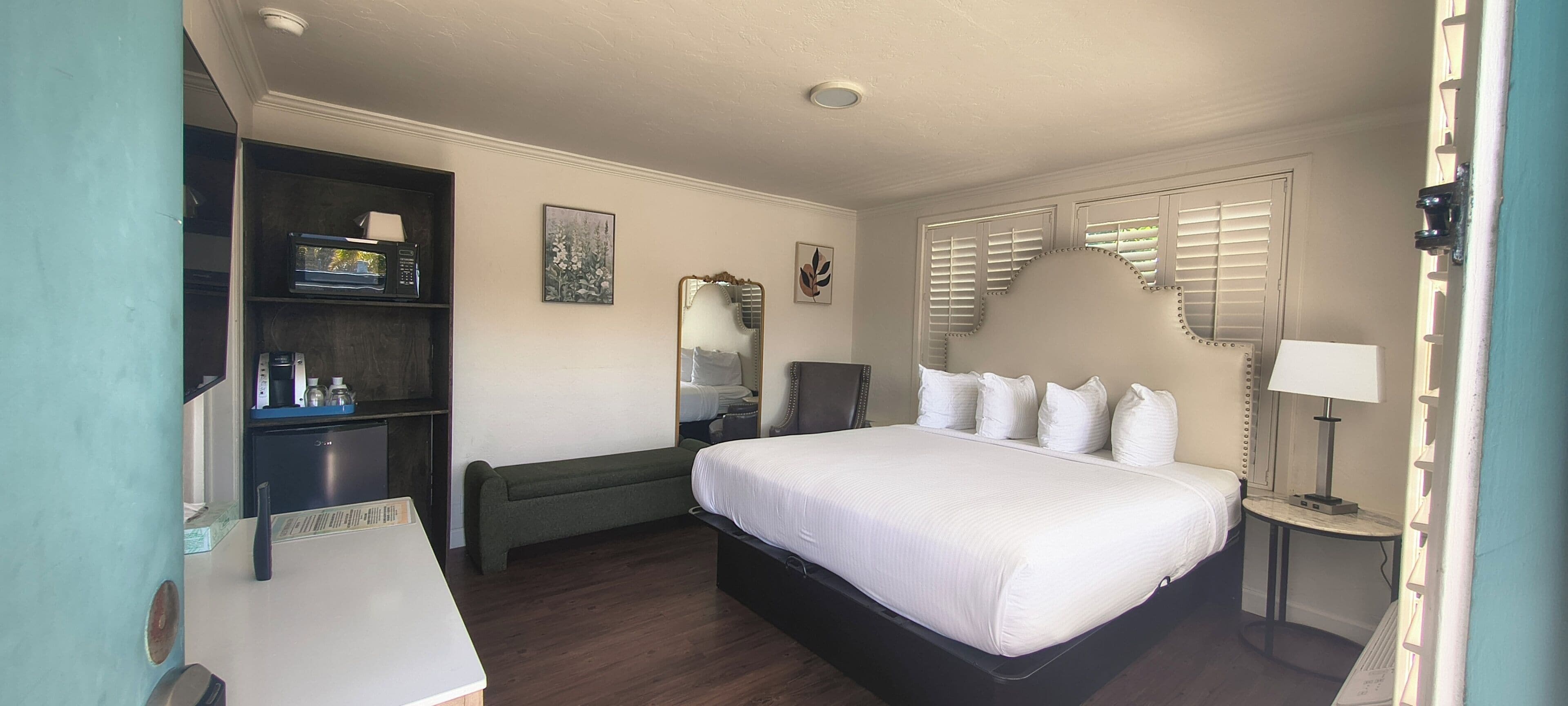 A bedroom with a bed, bedside table, lamp, and a small desk with a chair.