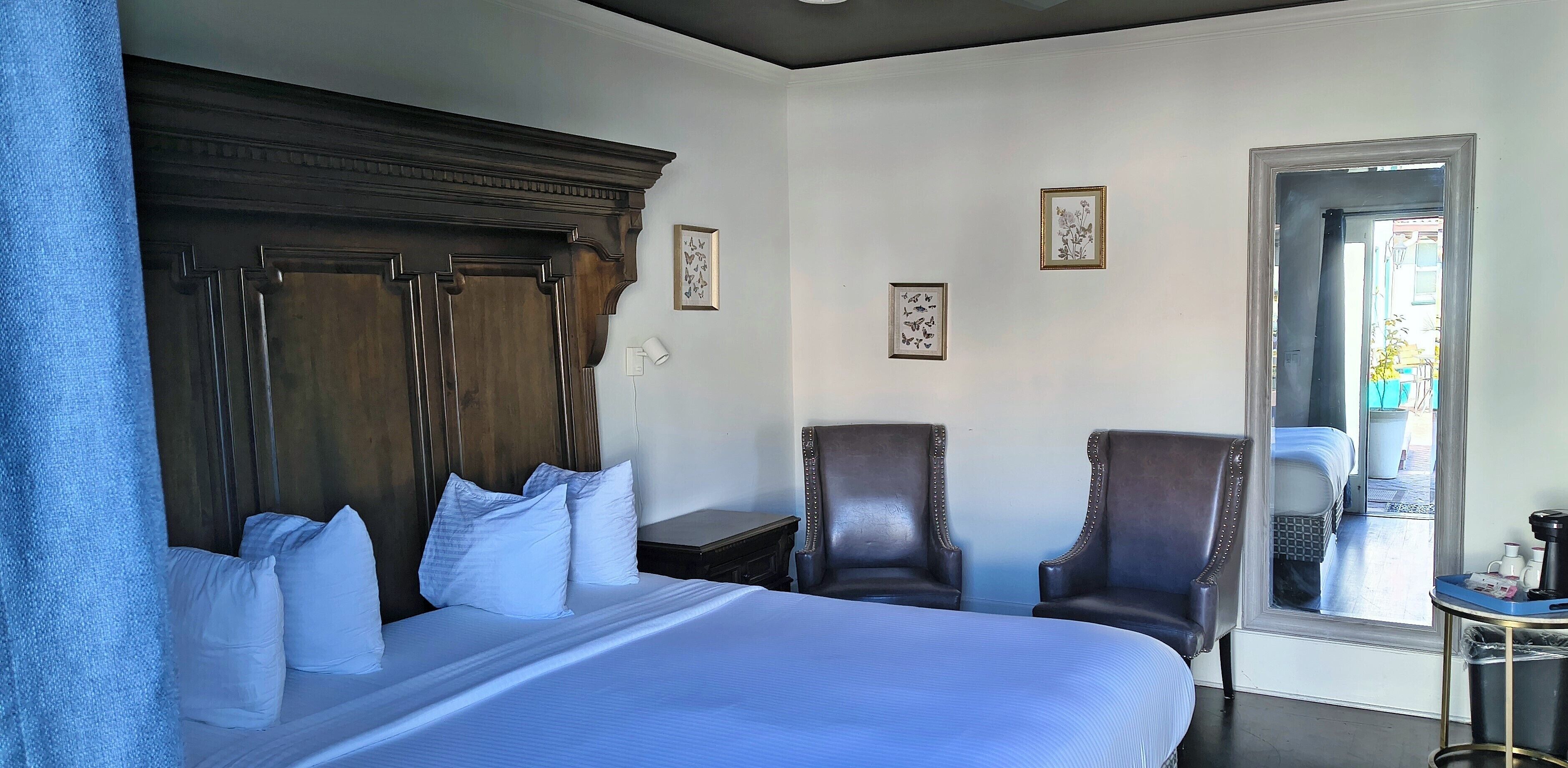 Een hotelkamer met een groot bed, twee fauteuils, een kleine tafel en een raam met uitzicht.