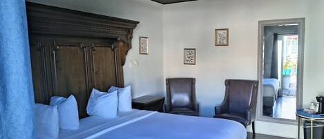 Een hotelkamer met een groot bed, twee fauteuils, een kleine tafel en een raam met uitzicht.