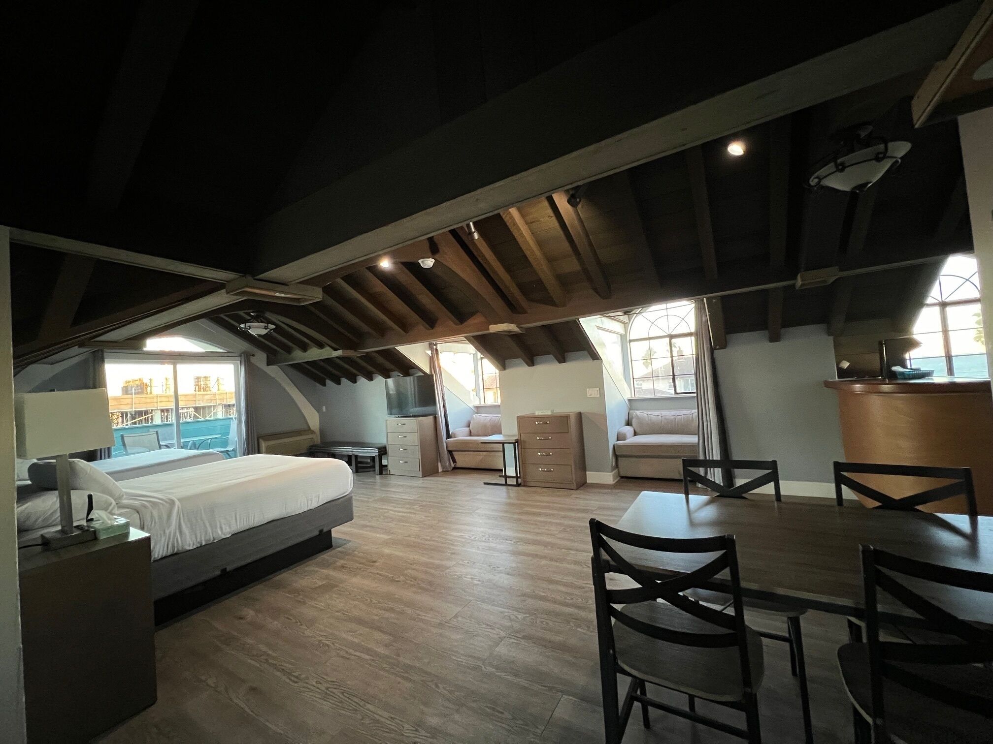 A spacious attic bedroom with a large bed, a desk, and a dining table.