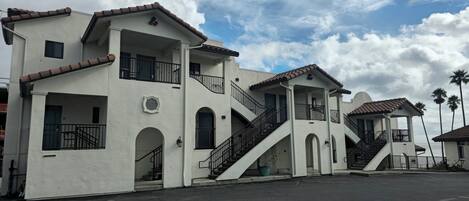 A row of white buildings with multiple balconies and staircases, likely part of a hotel or resort.