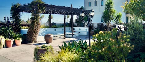 A covered patio area with potted plants and a pool.
