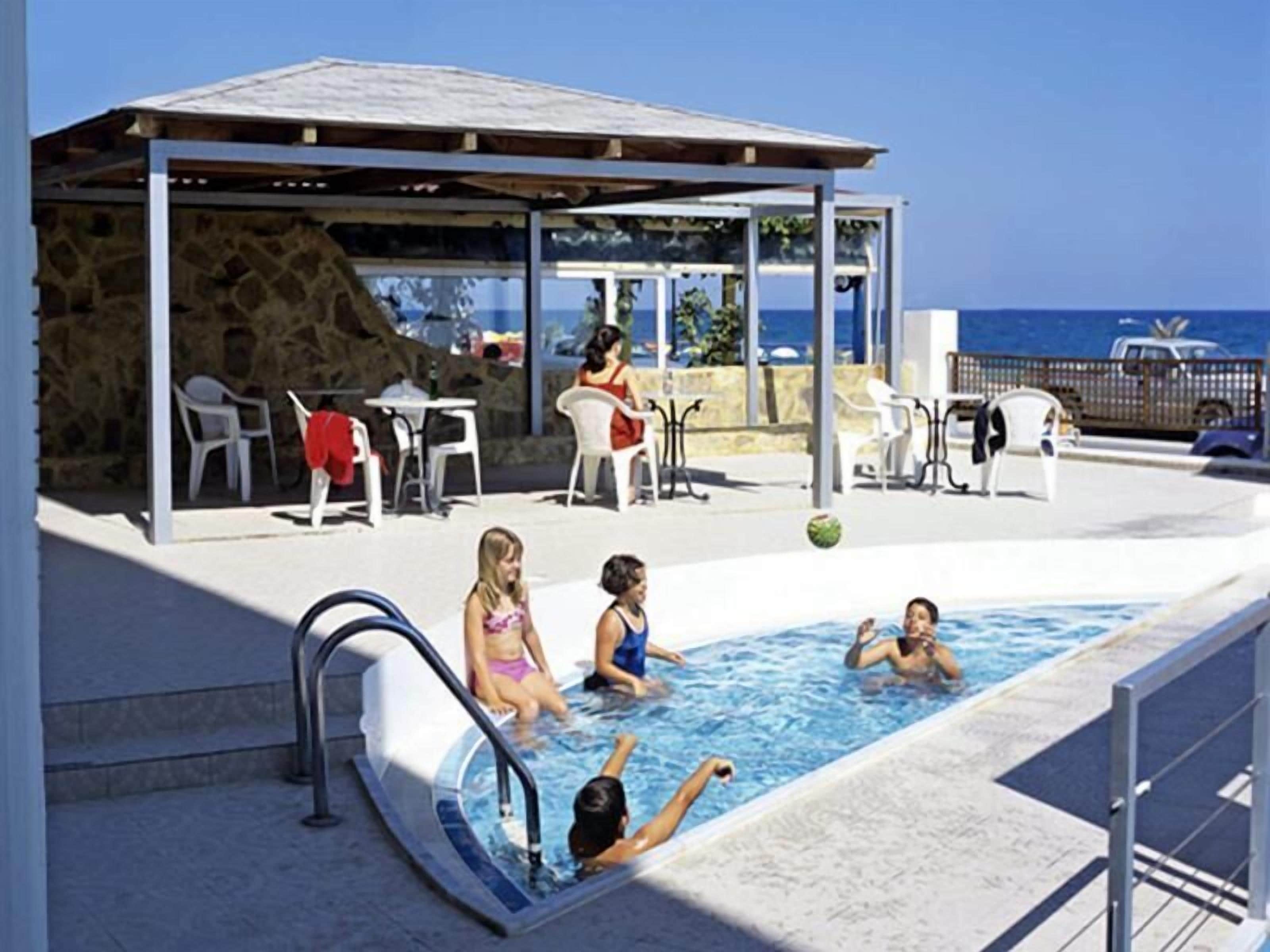 Una piscina al aire libre, sombrillas, sillones reclinables de piscina