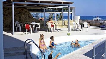 Una piscina al aire libre, sombrillas, sillones reclinables de piscina