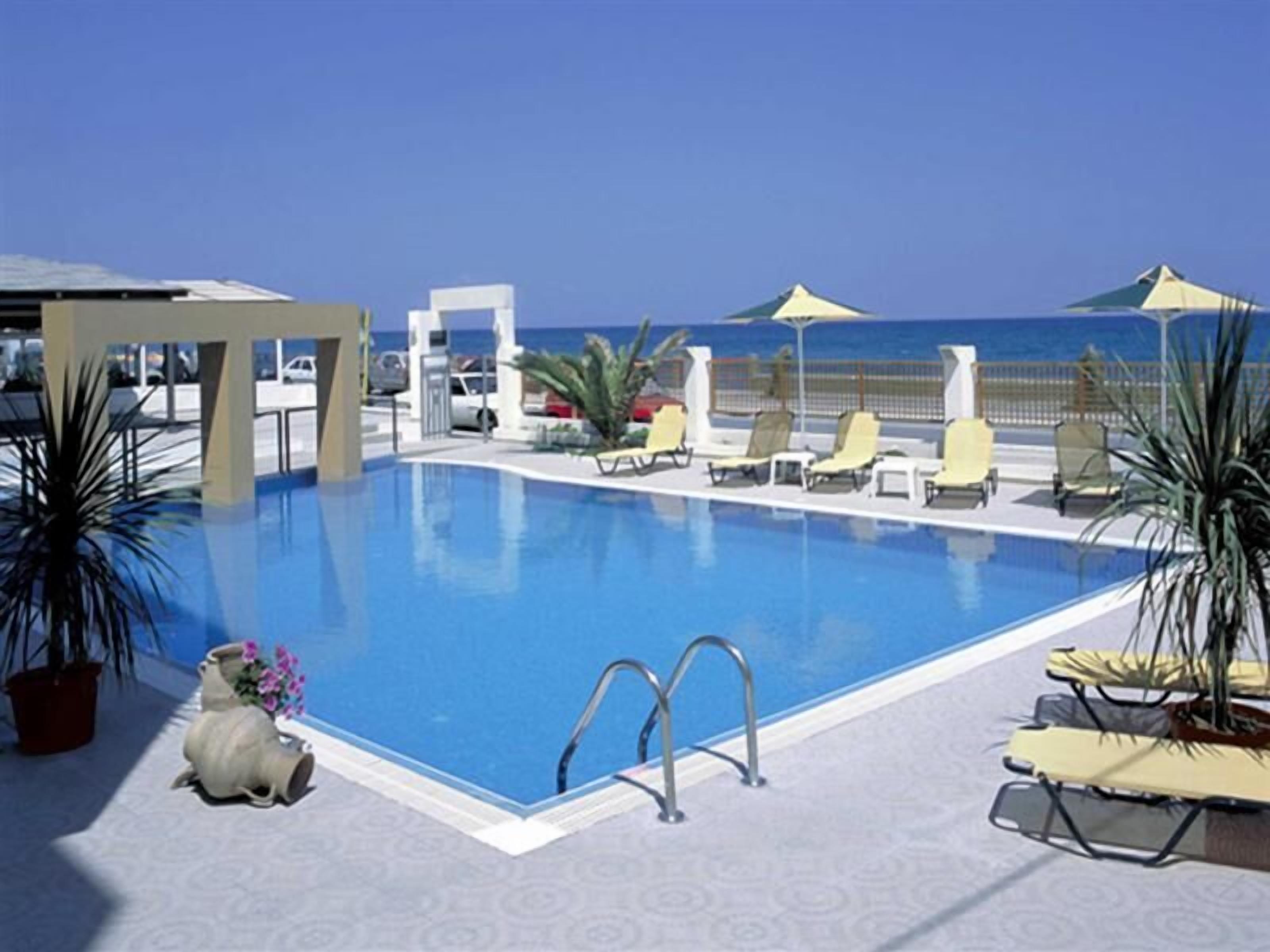 Una piscina al aire libre, sombrillas, sillones reclinables de piscina