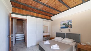 A bedroom with a bed, bedside tables, a desk, and a wardrobe. - Olympic Suites Hotel Apartments (Rethymno)