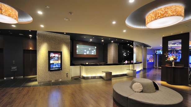 A modern lobby with a reception desk, a large flat-screen TV, and a comfortable seating area. - Dormy Inn Premium Shibuya Jingumae Hot Spring (Tokyo)