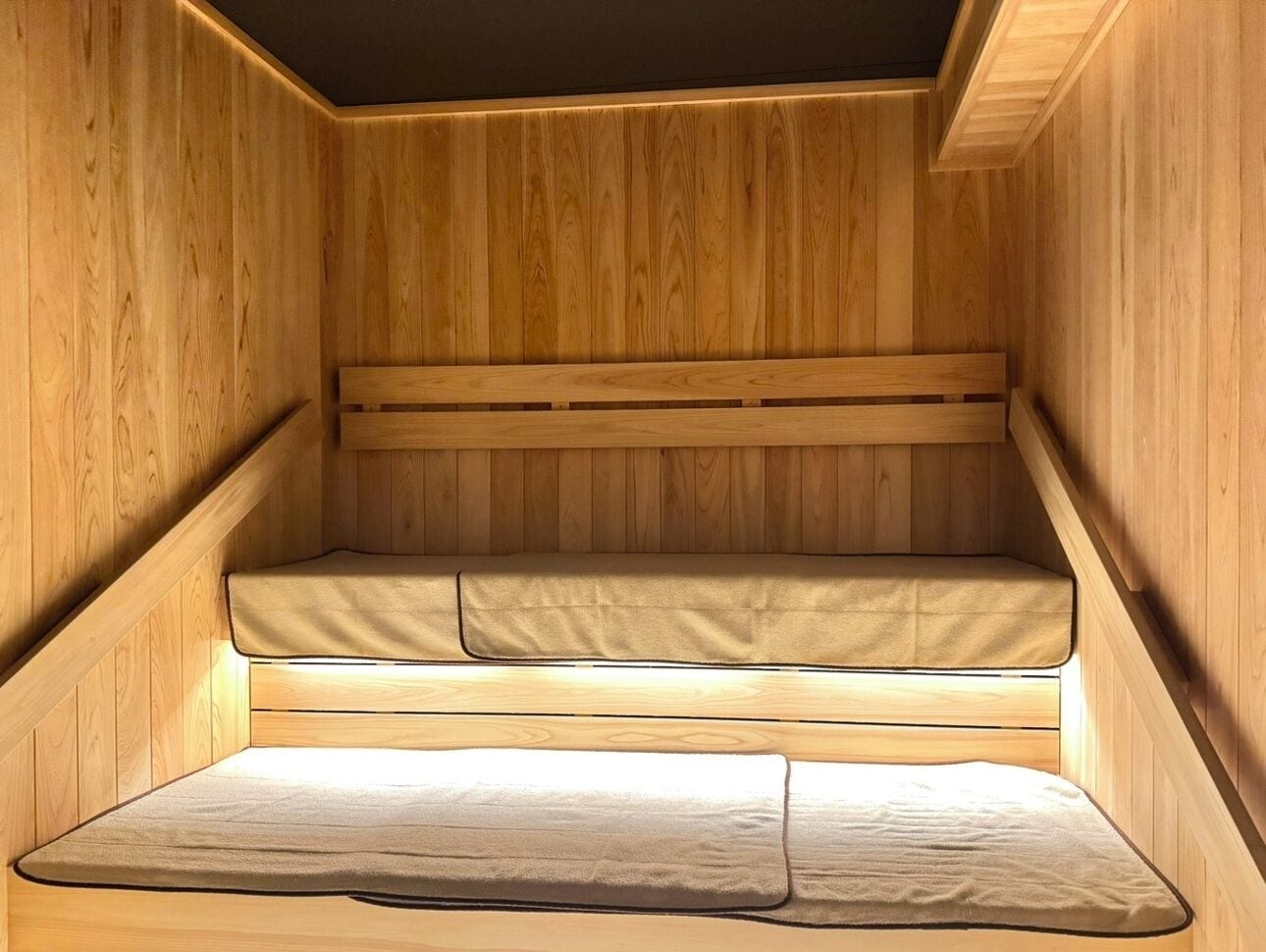 A wooden sauna with three levels of seating.