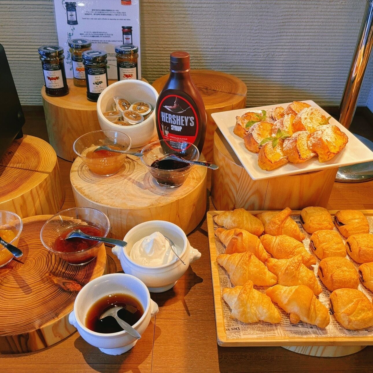 A table with various food items including pastries, condiments, and a bottle of Hershey's syrup.