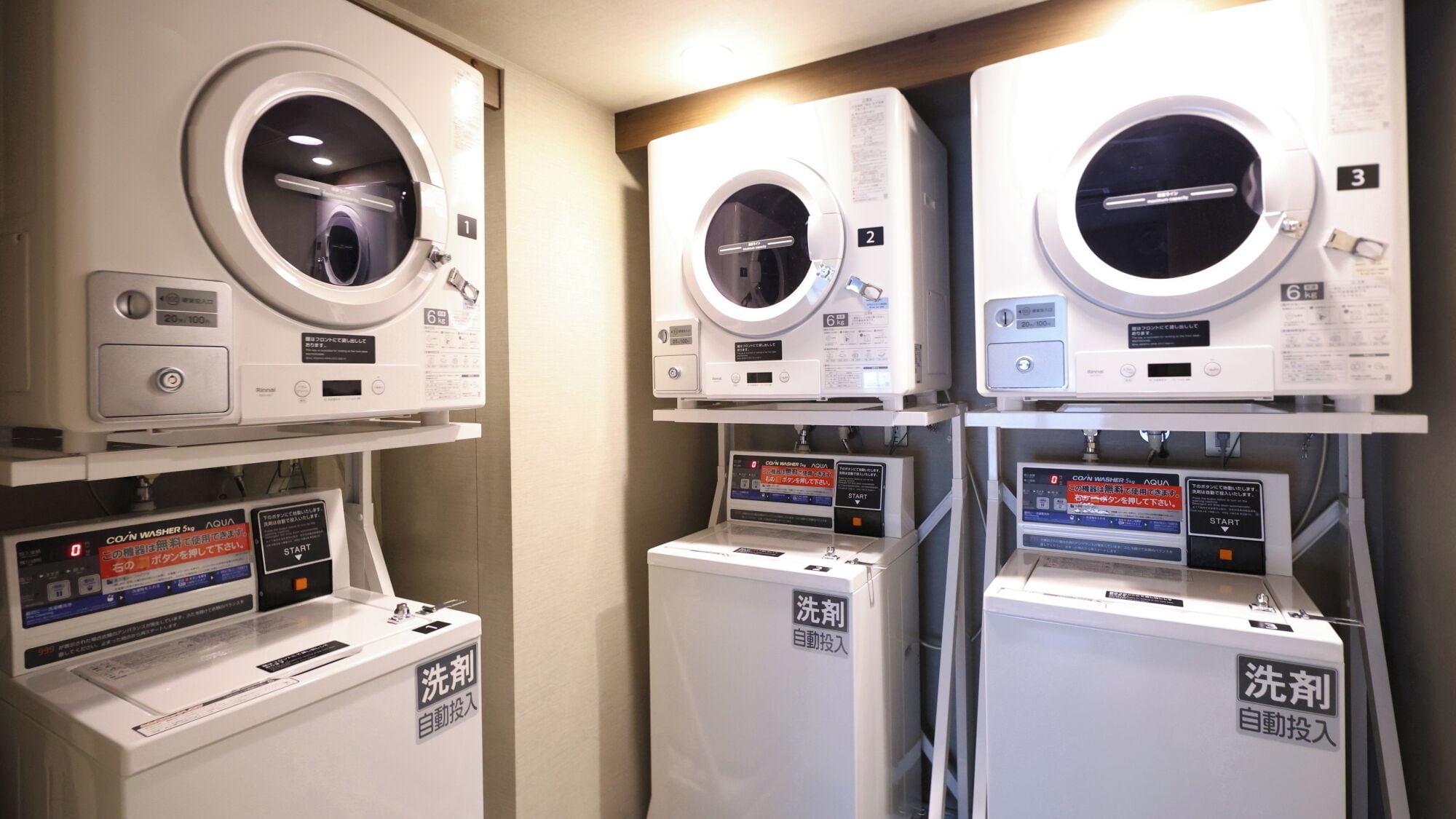 A row of three front-loading washing machines with control panels, each labeled with a number.