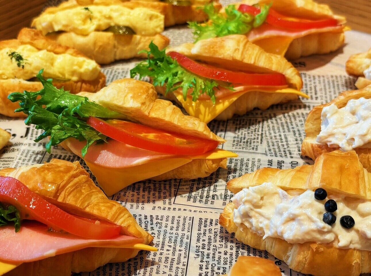 A variety of sandwiches and pastries on a newspaper background.