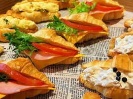 A variety of sandwiches and pastries on a newspaper background.
