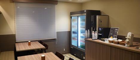A hotel room with a dining area, a refrigerator, and a coffee station.